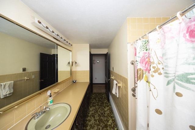 bathroom with a shower with shower curtain, a wainscoted wall, tile walls, and vanity