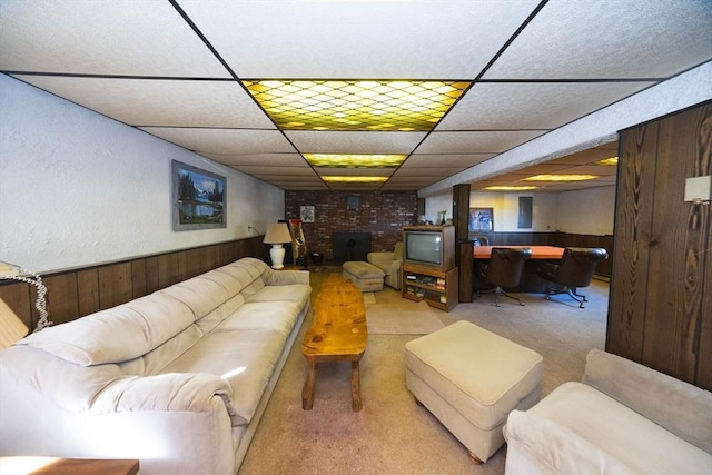 living area featuring a wainscoted wall, a drop ceiling, carpet flooring, and wooden walls