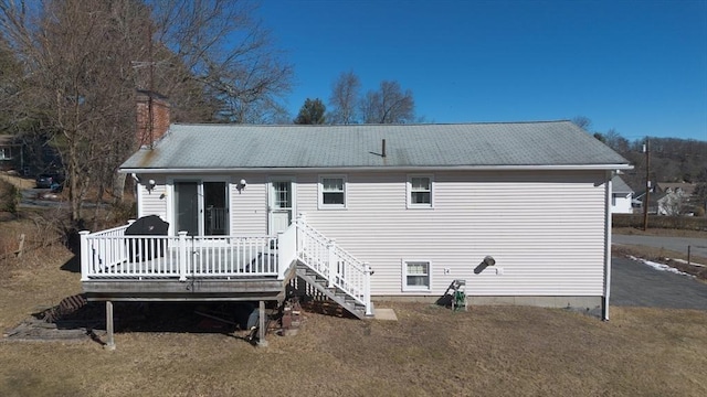 rear view of property featuring a chimney, a wooden deck, and stairs