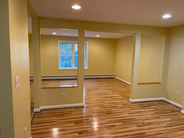 unfurnished room featuring a baseboard radiator and light hardwood / wood-style flooring