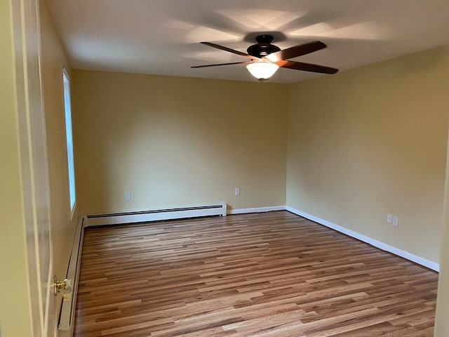 spare room featuring ceiling fan, a baseboard heating unit, and light hardwood / wood-style flooring