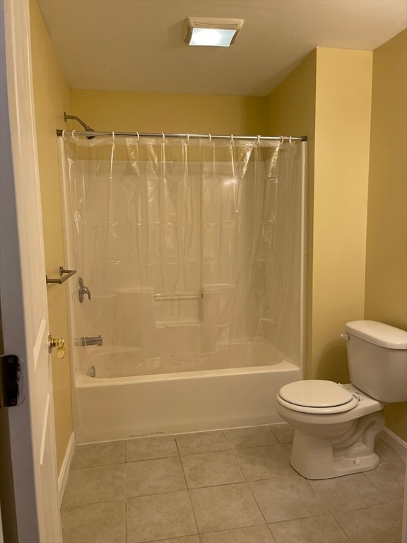 bathroom featuring shower / tub combo, tile patterned flooring, and toilet