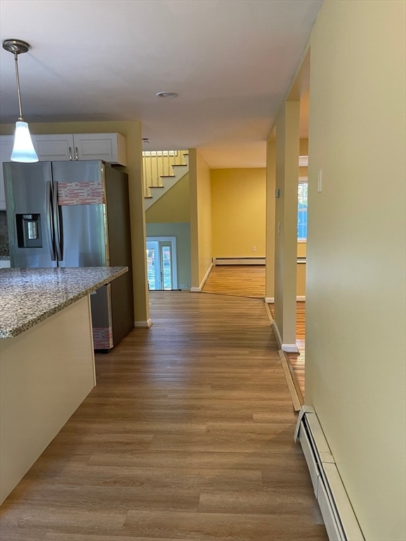 hallway featuring light hardwood / wood-style flooring, a baseboard heating unit, and a healthy amount of sunlight