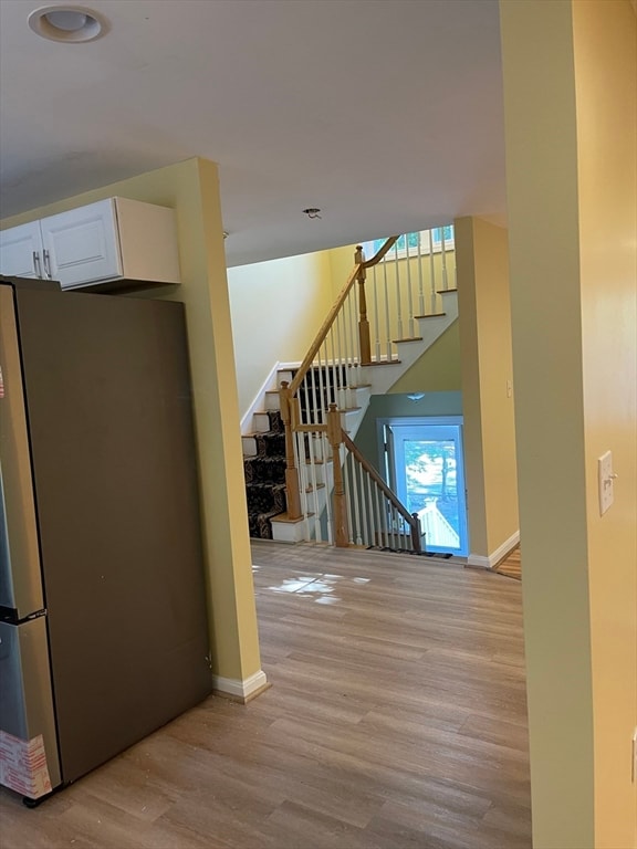 interior space featuring light hardwood / wood-style flooring, stainless steel fridge, and white cabinetry