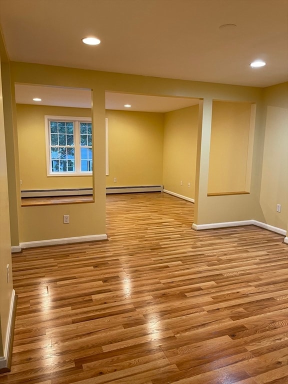 basement featuring baseboard heating and light hardwood / wood-style flooring