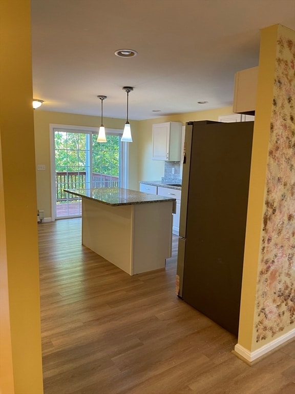 kitchen featuring a kitchen island, white cabinets, stainless steel fridge, light hardwood / wood-style floors, and pendant lighting