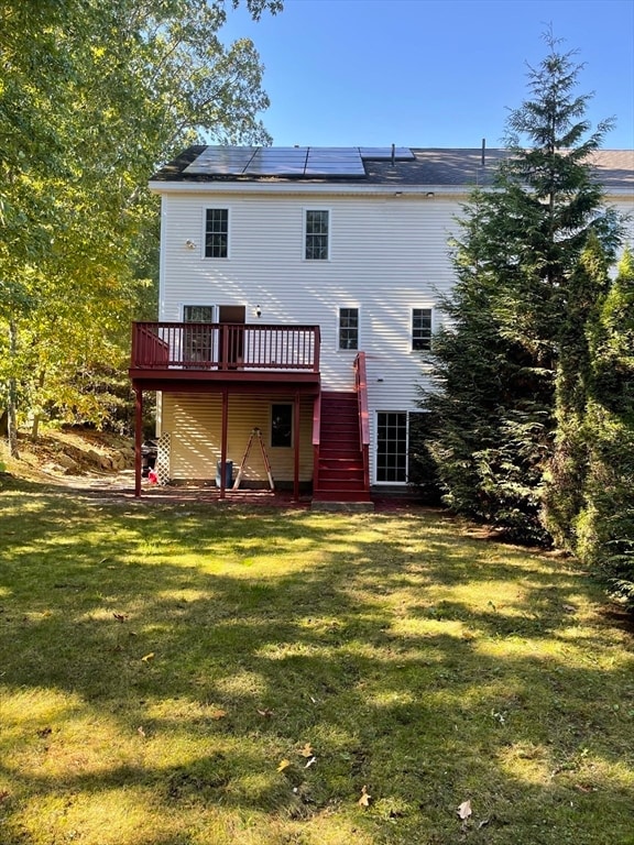 rear view of house featuring a lawn and a deck