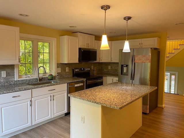 kitchen with white cabinetry, appliances with stainless steel finishes, a kitchen island, and sink