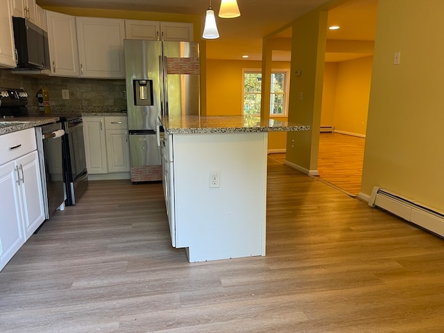 kitchen with light hardwood / wood-style floors, hanging light fixtures, white cabinetry, and stainless steel appliances