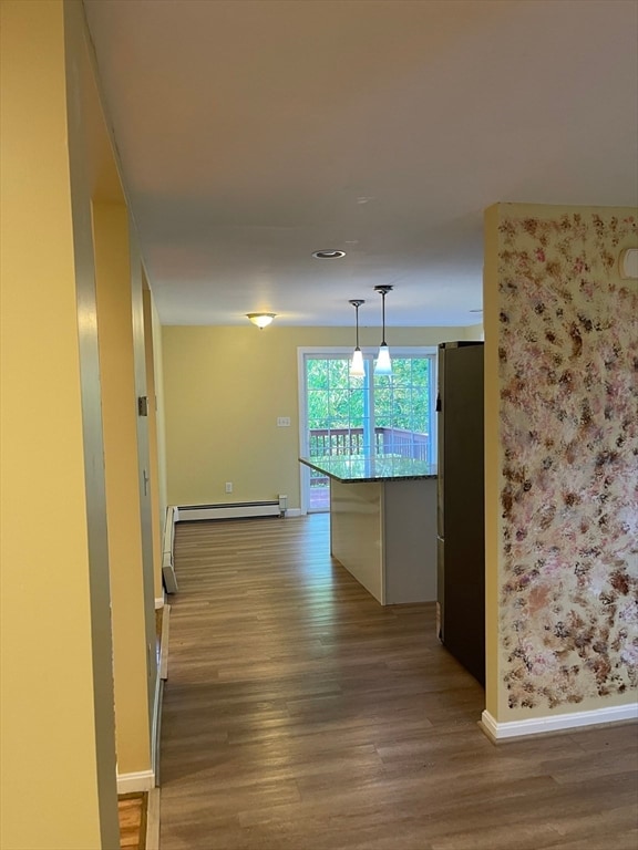 corridor with wood-type flooring and baseboard heating