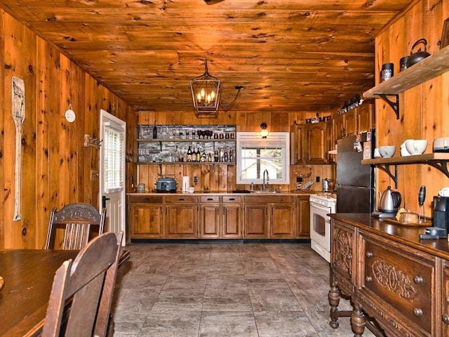 kitchen featuring sink, hanging light fixtures, white range with gas stovetop, wooden walls, and wood ceiling