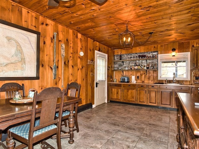 dining room featuring a notable chandelier, sink, and wooden walls