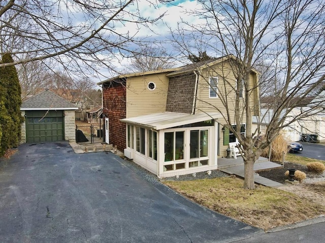 view of front of property featuring a sunroom, an outdoor structure, and a garage