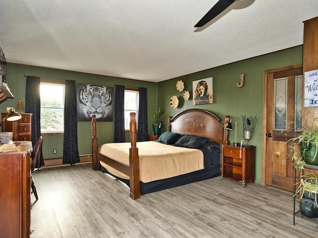 bedroom with ceiling fan, light hardwood / wood-style floors, and a textured ceiling