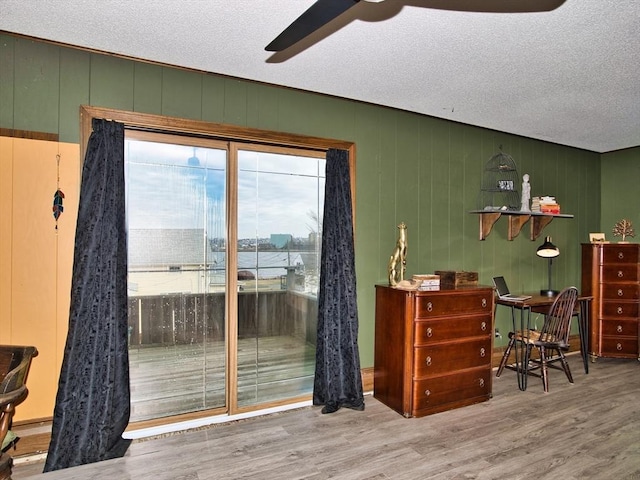 interior space with wood walls, a textured ceiling, and hardwood / wood-style flooring