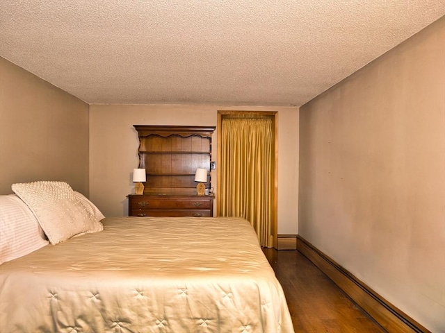 bedroom featuring baseboard heating, dark hardwood / wood-style flooring, and a textured ceiling