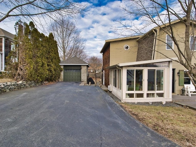 view of property exterior featuring a sunroom, an outdoor structure, and a garage