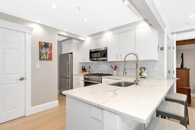 600 Shirley St Unit 3, Winthrop, MA 02152 - kitchen featuring appliances with stainless steel finishes, a sink, a peninsula, light wood finished floors, and decorative backsplash