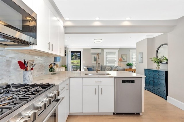 600 Shirley St Unit 3, Winthrop, MA 02152 - kitchen with appliances with stainless steel finishes, a sink, a peninsula, tasteful backsplash, and white cabinets