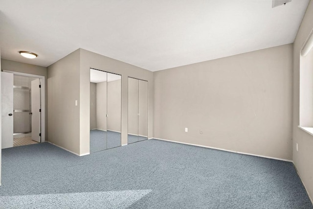 unfurnished bedroom with two closets and carpet floors