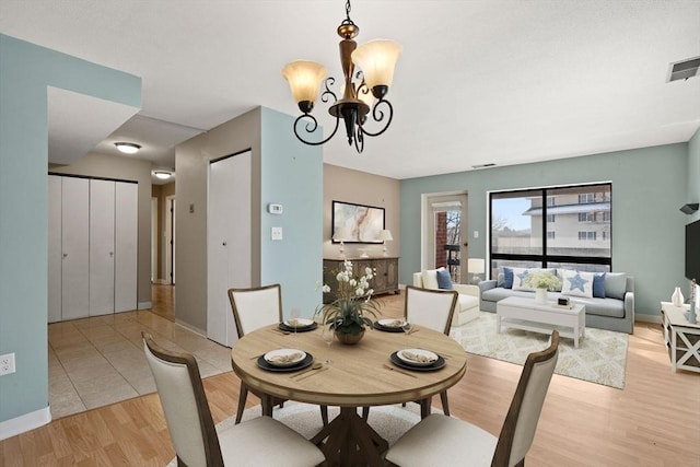 dining room with light hardwood / wood-style flooring and an inviting chandelier