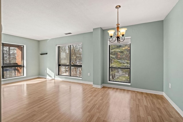 unfurnished dining area featuring light hardwood / wood-style floors, an inviting chandelier, and a healthy amount of sunlight