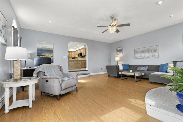 living area featuring baseboards, arched walkways, a ceiling fan, light wood-type flooring, and recessed lighting