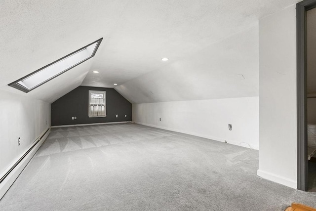 bonus room with baseboards, lofted ceiling with skylight, a baseboard radiator, a textured ceiling, and carpet flooring