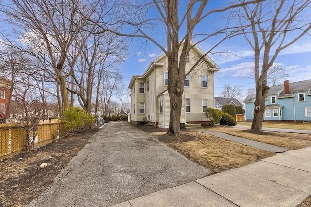 view of property exterior featuring a residential view, fence, and driveway