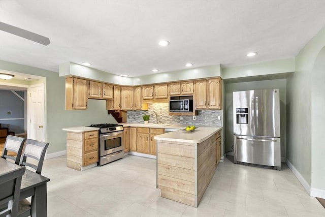 kitchen with stainless steel appliances, light countertops, decorative backsplash, light brown cabinets, and baseboards