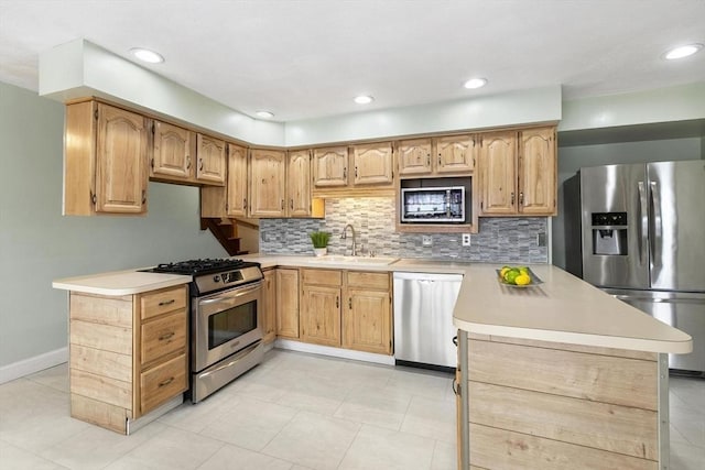 kitchen with stainless steel appliances, backsplash, a sink, and a peninsula