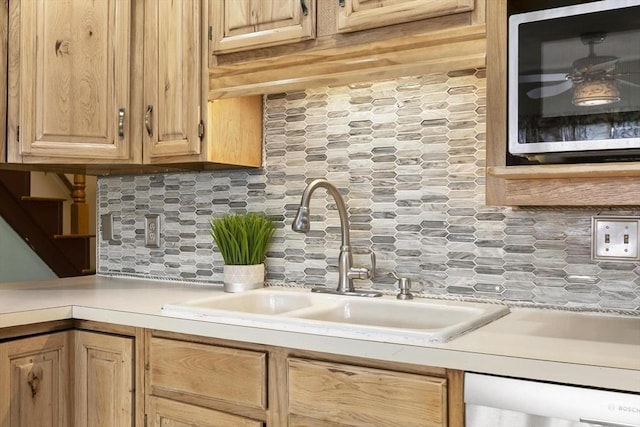 kitchen with dishwashing machine, tasteful backsplash, light countertops, and a sink