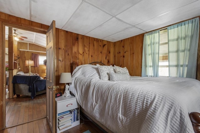 bedroom with wooden walls, multiple windows, and hardwood / wood-style floors