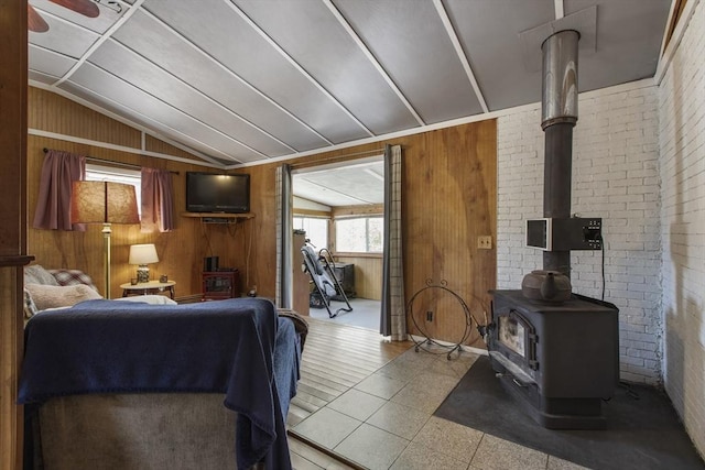 living area with wood walls, vaulted ceiling, and a wood stove
