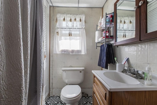 bathroom featuring toilet, tile walls, decorative backsplash, and vanity