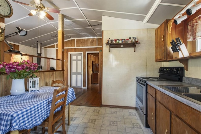 kitchen featuring wooden walls, ceiling fan, vaulted ceiling, and black range with electric stovetop