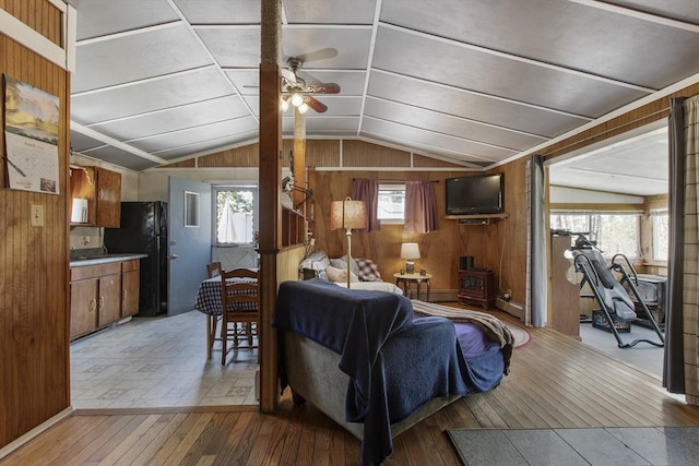 living room with wooden walls, ceiling fan, lofted ceiling, and light wood finished floors