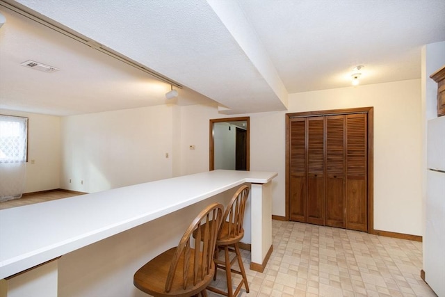 kitchen with a kitchen breakfast bar, kitchen peninsula, and white fridge