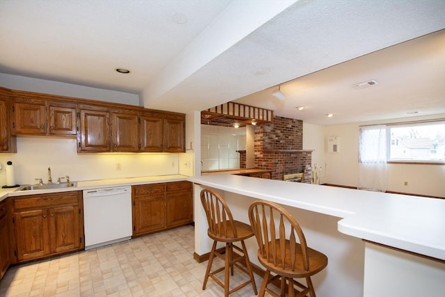 kitchen with a breakfast bar area, white dishwasher, kitchen peninsula, and sink