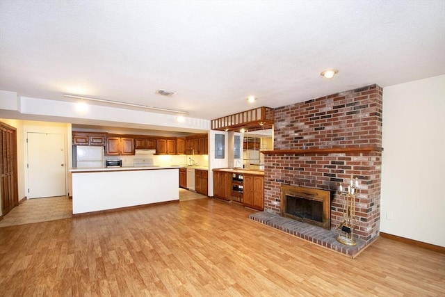 unfurnished living room with a fireplace, sink, and light hardwood / wood-style flooring