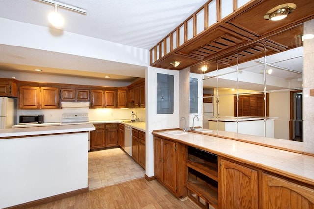 kitchen with kitchen peninsula, sink, white appliances, and light hardwood / wood-style flooring