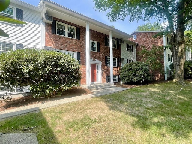 view of front facade featuring a front yard and a wall mounted AC