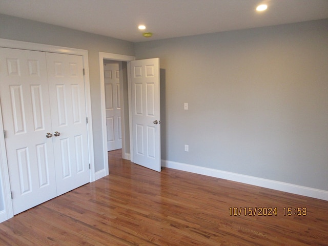 unfurnished bedroom featuring a closet and dark wood-type flooring