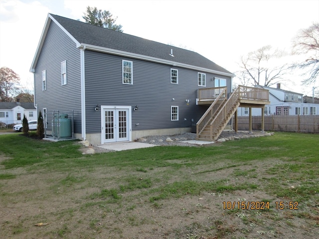 back of house with french doors, a deck, and a lawn