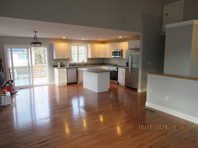 kitchen featuring stainless steel appliances, white cabinetry, dark hardwood / wood-style floors, a kitchen island, and hanging light fixtures