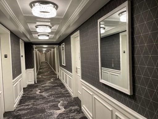 151 Tremont St Unit 9N, Boston, MA 02111 - corridor with a raised ceiling, a decorative wall, a chandelier, dark colored carpet, and crown molding