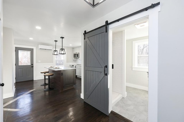 kitchen with a kitchen breakfast bar, pendant lighting, an AC wall unit, white cabinets, and a kitchen island