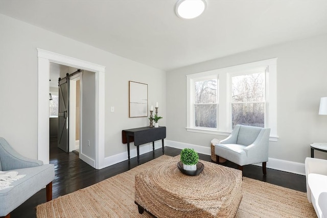 living area with a barn door and dark hardwood / wood-style flooring