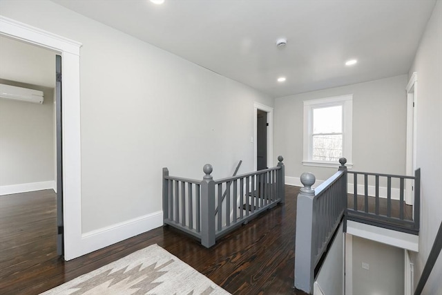 corridor with a wall mounted air conditioner and dark hardwood / wood-style floors