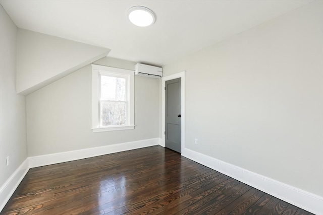 additional living space with dark hardwood / wood-style flooring and a wall unit AC